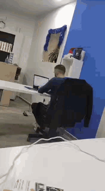 a man is sitting at a desk in front of a laptop computer