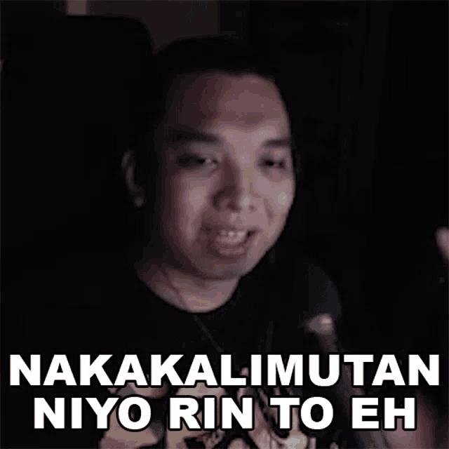 a man is talking into a microphone and making a funny face while wearing a black shirt .