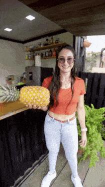 a woman is holding a pineapple in her hand and smiling