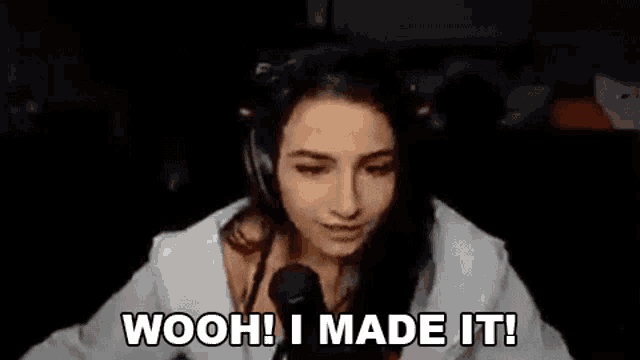 a woman wearing headphones is sitting in front of a microphone and saying woohoo ! i made it !