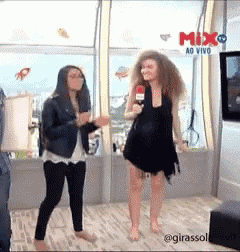 two women are dancing in front of a sign that says mix on it