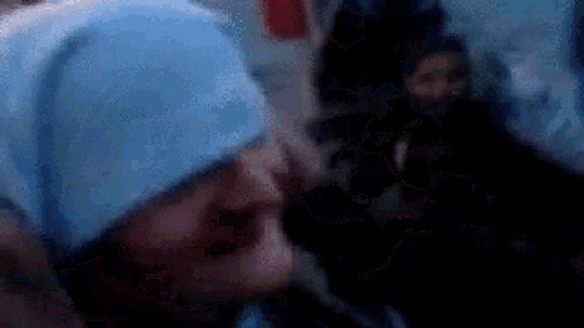 a blurry picture of a person wearing a blue hat and a scarf .