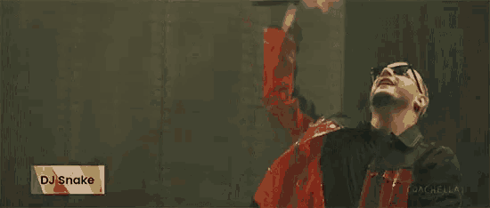 a man in a red jacket is holding a microphone in front of a dj snake logo