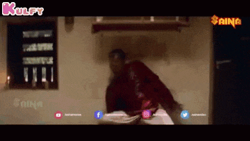 a man in a red jacket is standing in a room holding a book .