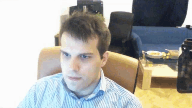 a man in a striped shirt sits in a chair