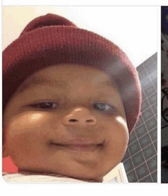 a baby wearing a red beanie is smiling for a picture .