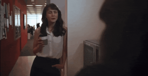 a woman standing in a hallway holding a coffee cup