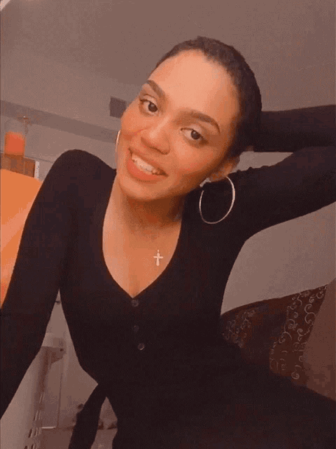 a woman wearing a black sweater with a cross necklace