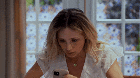 a woman is sitting at a table looking at her cell phone