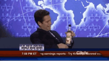 a man is holding a bottle in front of a world wide news sign