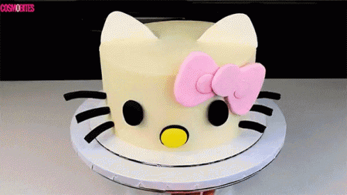 a white hello kitty cake with a pink bow on top