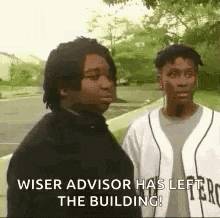 two men are standing next to each other on a sidewalk and talking .