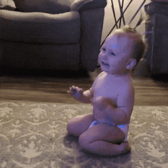 a baby in a diaper is sitting on the floor in a living room