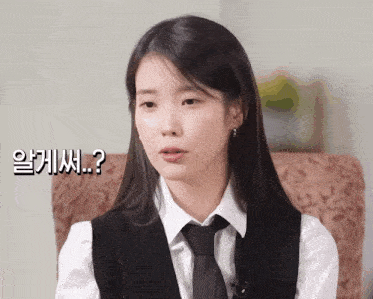 a woman in a white shirt and black tie is sitting in a chair with a question mark above her