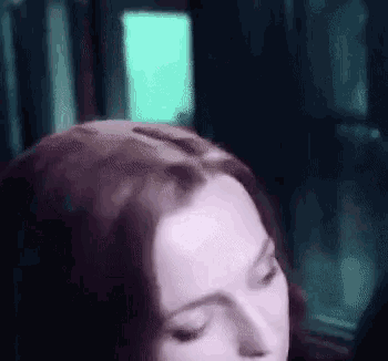 a close up of a woman 's head with her eyes closed in a dark room .