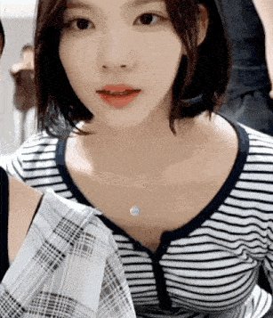 a close up of a woman wearing a striped shirt and a plaid skirt