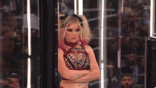 a woman with her arms crossed is standing in a room with a crowd behind her .