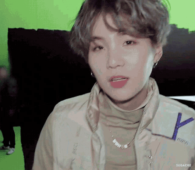 a close up of a person wearing a jacket and a necklace