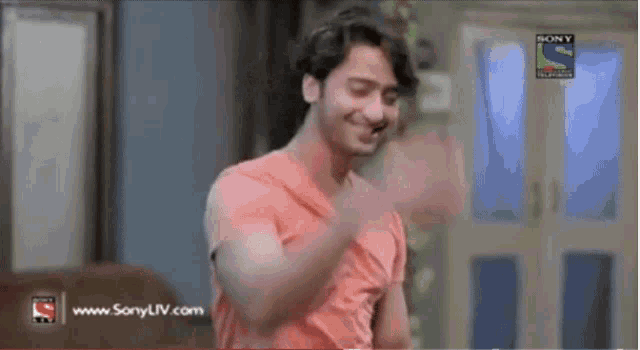 a man in a red shirt is dancing in front of a sony tv screen