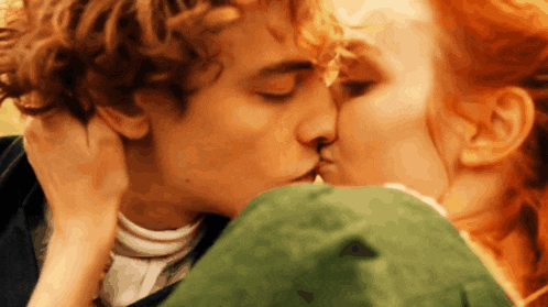 a man and a woman are kissing and the woman is wearing a green dress .