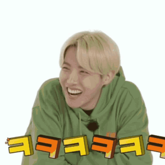 a man with blonde hair is wearing a green hoodie and laughing with yellow letters behind him .