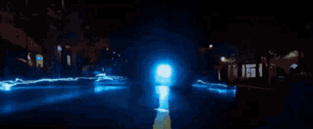 a car is driving down a street at night and a lightning bolt is coming out of the sky .