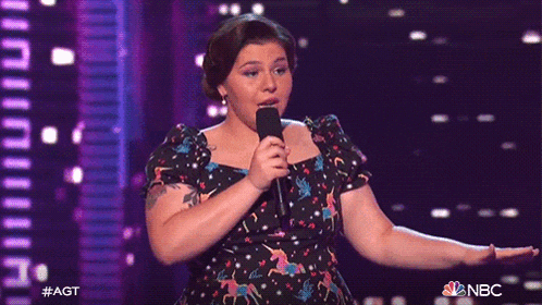 a woman in a polka dot dress is singing into a microphone on nbc
