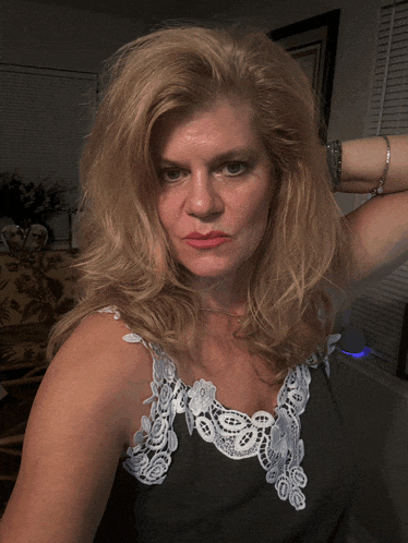 a woman with blonde hair is wearing a black tank top with white lace trim