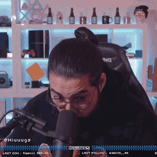 a man wearing glasses is sitting in front of a microphone with the hashtag @hiuuugs