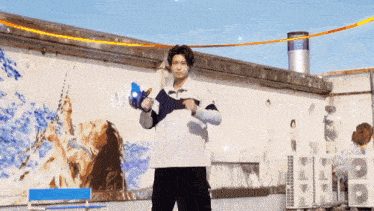 a man is standing in front of a wall with a painting of a woman holding a sword .