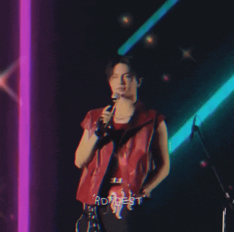 a man in a red vest is singing into a microphone with rdt best written on the screen
