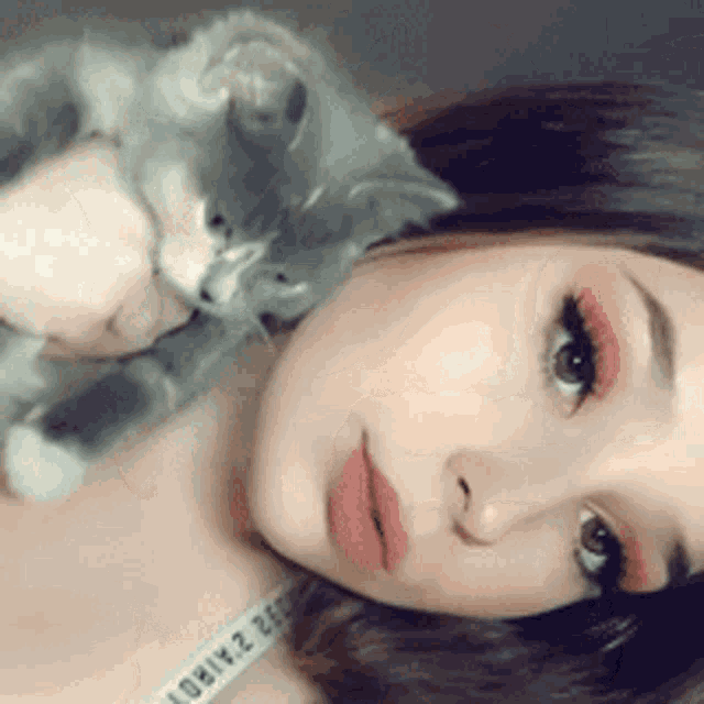 a woman is laying down with a cat and a measuring tape that says victoria 's secret