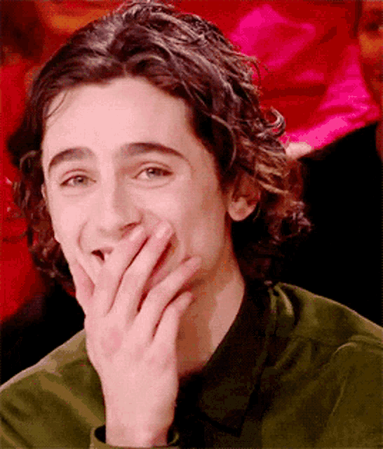 a young man covering his mouth with his hand and smiling