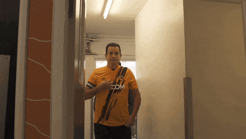 a man wearing a yellow shirt that says com on it