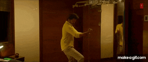 a man in a yellow shirt is dancing in a room next to a mirror .