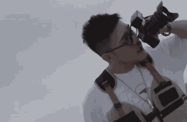 a man wearing glasses holds a camera over his head