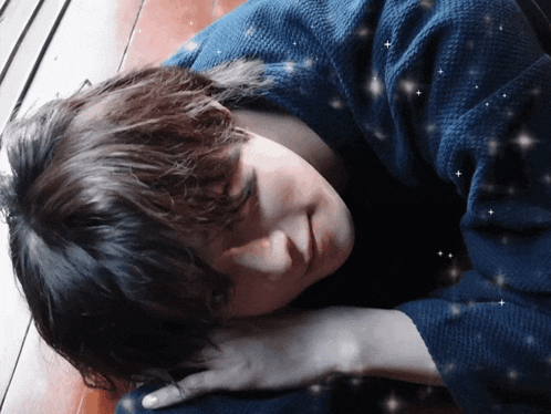 a person laying on a wooden floor with a blue shirt on
