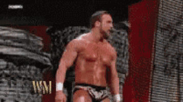 a shirtless wrestler is standing in front of a sign that says wm .