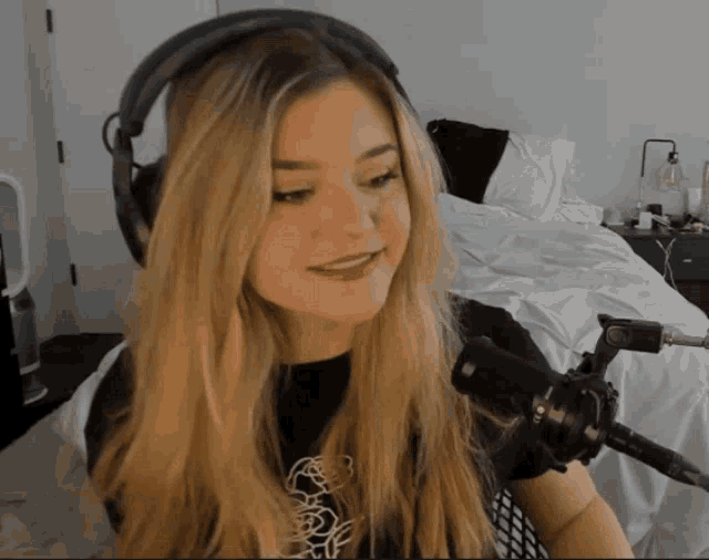 a woman wearing headphones stands in front of a microphone in a room