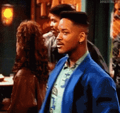 a man in a blue suit is standing in front of a woman in a bar .