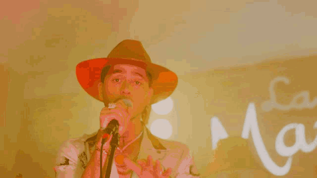 a man in a cowboy hat sings into a microphone