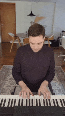a man in a purple shirt is playing a keyboard