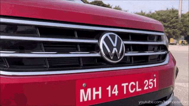 a close up of a red volkswagen with a license plate that says mh 14 tcl 251