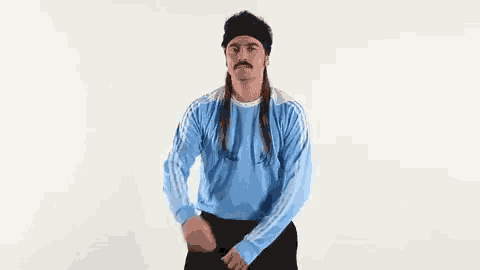 a man with long hair and a mustache is wearing a blue adidas sweater and a headband .