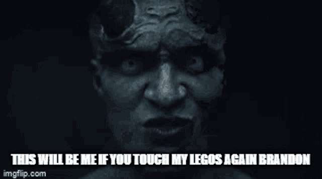 a devil with horns and teeth is making a funny face in a dark room .