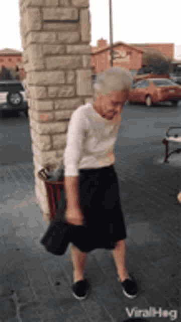 an elderly woman is dancing in front of a brick wall ..
