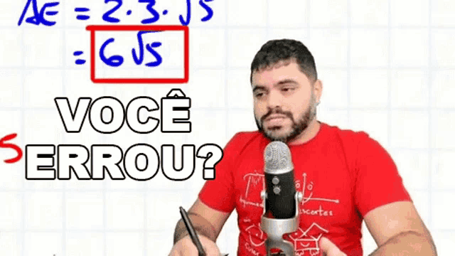 a man in a red shirt is holding a microphone in front of a whiteboard .
