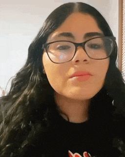 a woman wearing glasses and a black shirt is making a face .