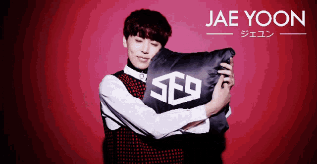 a young man holding a pillow with the letters sfg on it