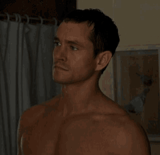 a shirtless man is standing in front of a curtain